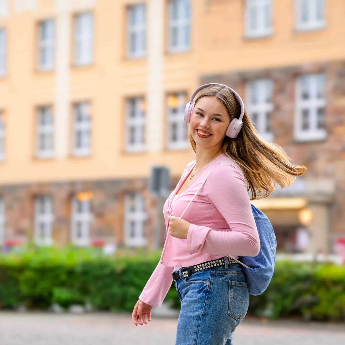Junge Frau mit Kopfhörern und Rucksack unterwegs in Wilhelmshaven – Symbol für Energie, Lebensfreude und moderne Produkte der GEW Wilhelmshaven.